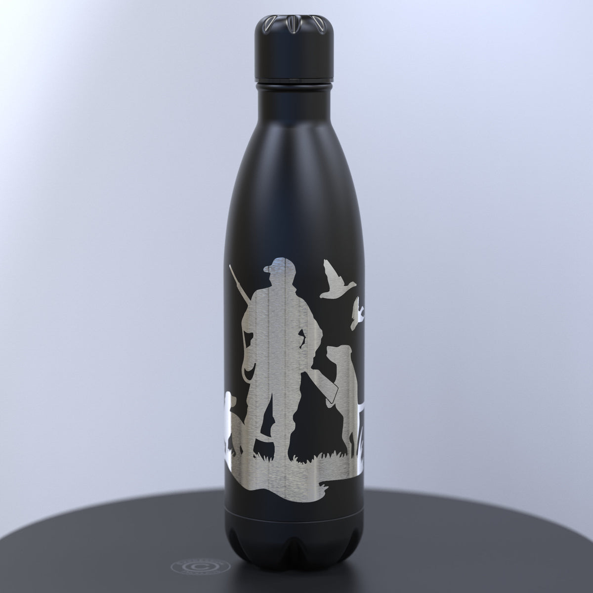 A matte black insulated water bottle with a lid, featuring a silver etched graphic of a duck hunter silhouette with ducks and a dog 