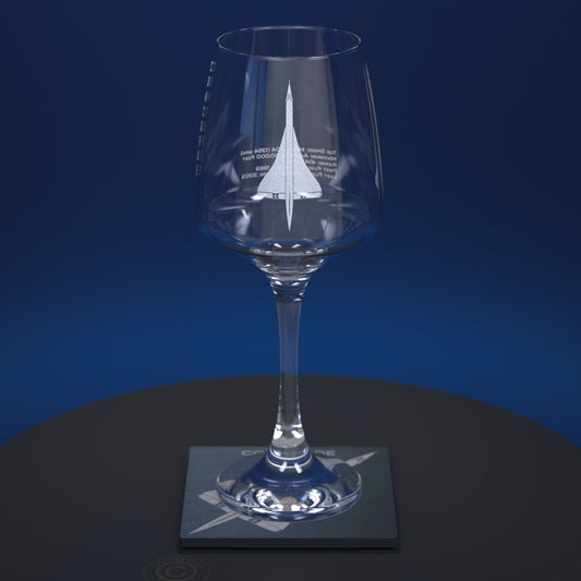 A clear stemmed wine glass with a white etched Concorde design and text on the bowl, displayed on a square slate coaster against a dark blue gradient background.