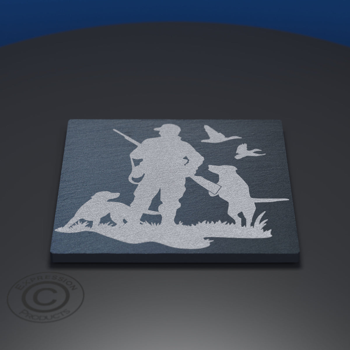 A rectangular slate coaster featuring a white laser-engraved silhouette of a duck hunter with a rifle, standing beside two dogs and two flying ducks, displayed on a dark gray surface.